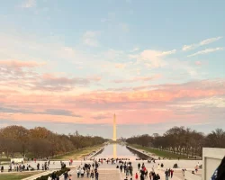 a sunset photo of the monument with many people